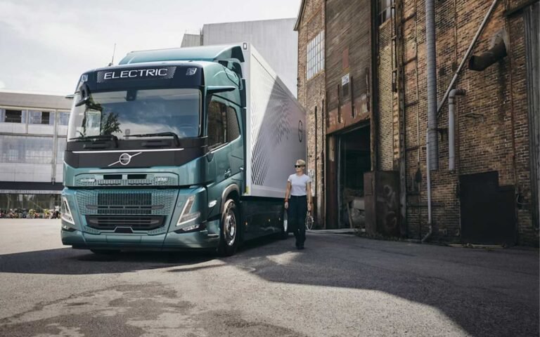 Tractocamión Volvo con su operador frente a una nave industrial de ladrillo