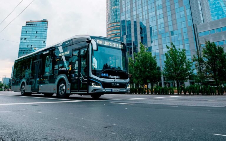 Autobús eléctrico urbano circulando por una avenida con edificios de vidrio