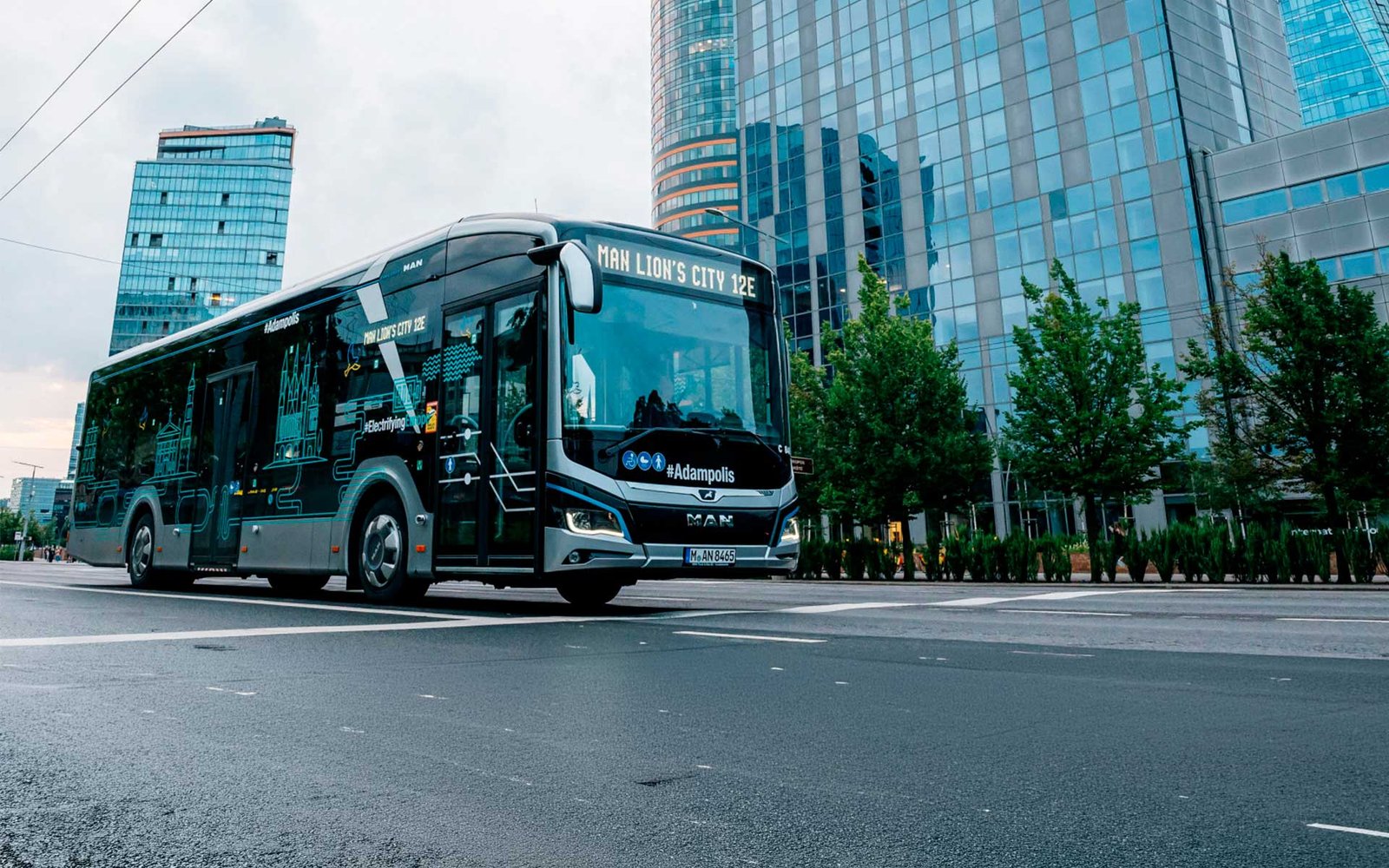 Autobús eléctrico urbano circulando por una avenida con edificios de vidrio