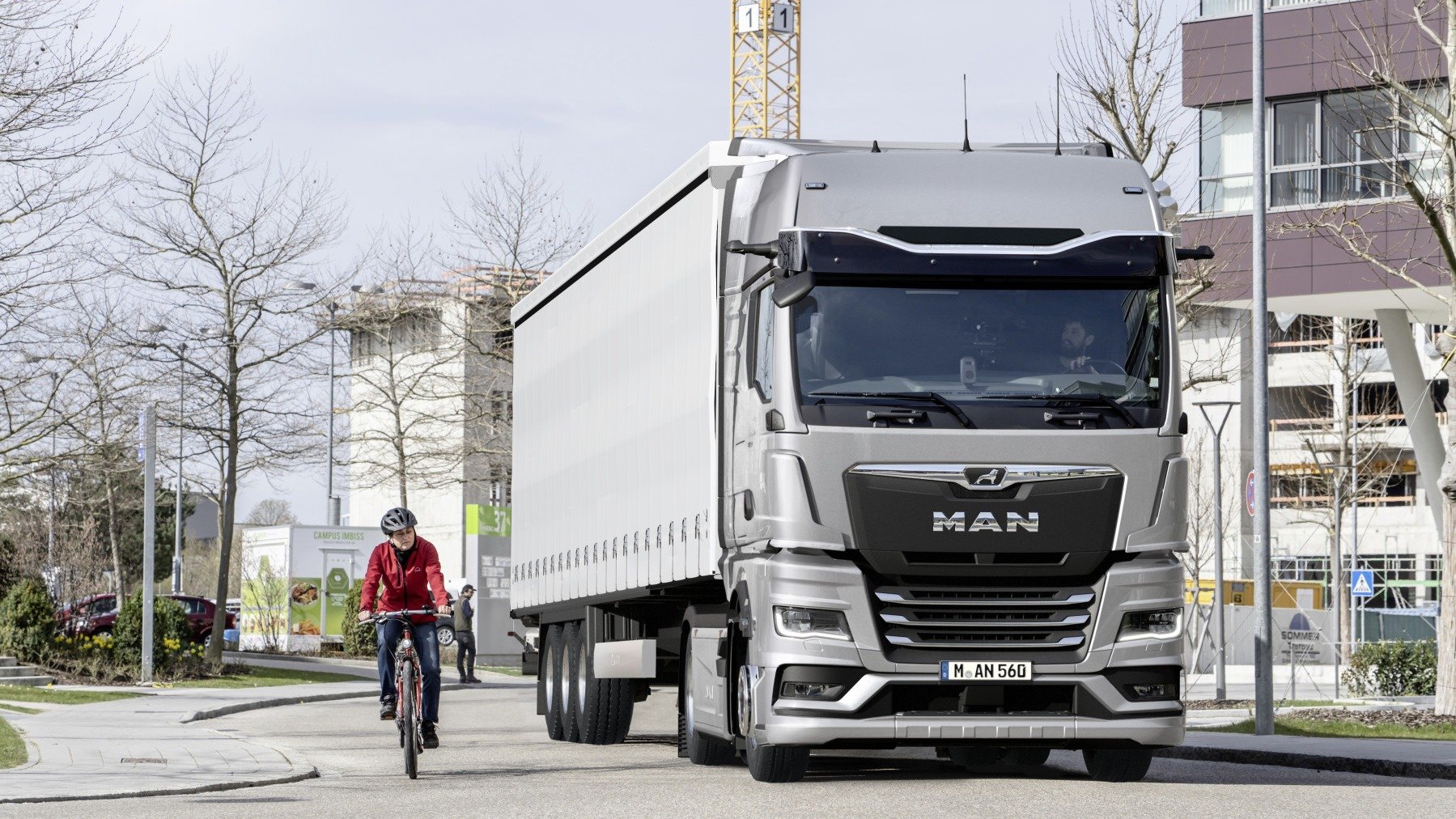 Tractocamión MAN TGX en una calle urbana junto a un ciclista